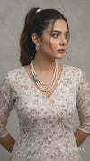 Pearl necklace with diamond and gemstone clasp on a black stand, with matching earrings.